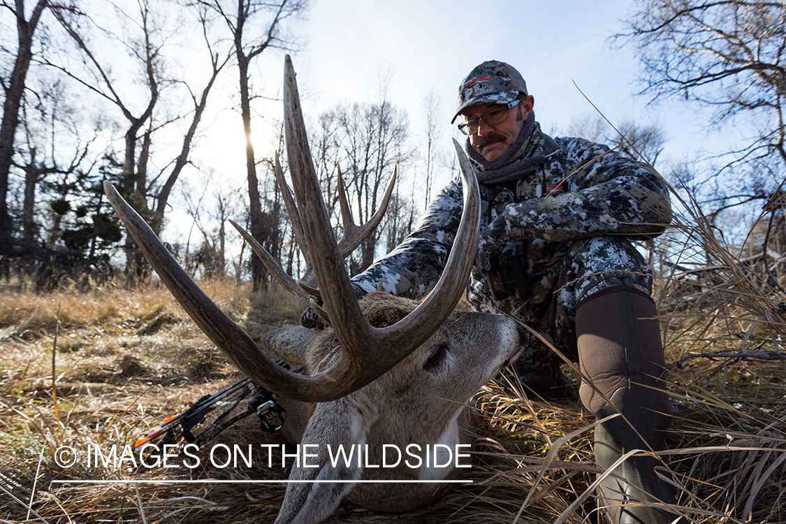 Bow hunter with downed white-tailed deer.