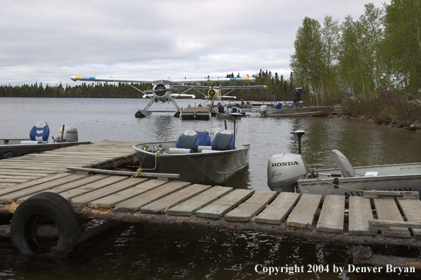 Float plane and fishing boats tied up to the dock at dusk.  Saskatchewan.