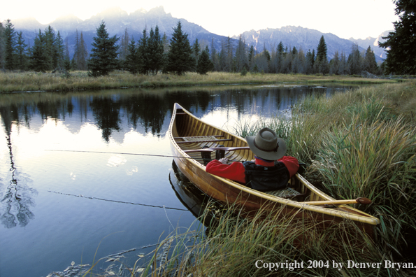 Flyfisherman in wooden cedar canoe.  Teton mountains in background.