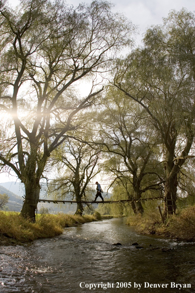 Flyfisherman crossing foot bridge over Pennsylvania spring creek.