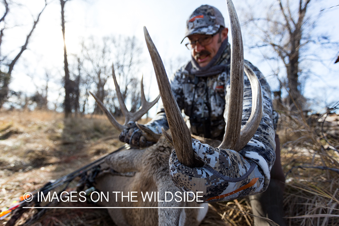 Bow hunter with downed white-tailed deer.