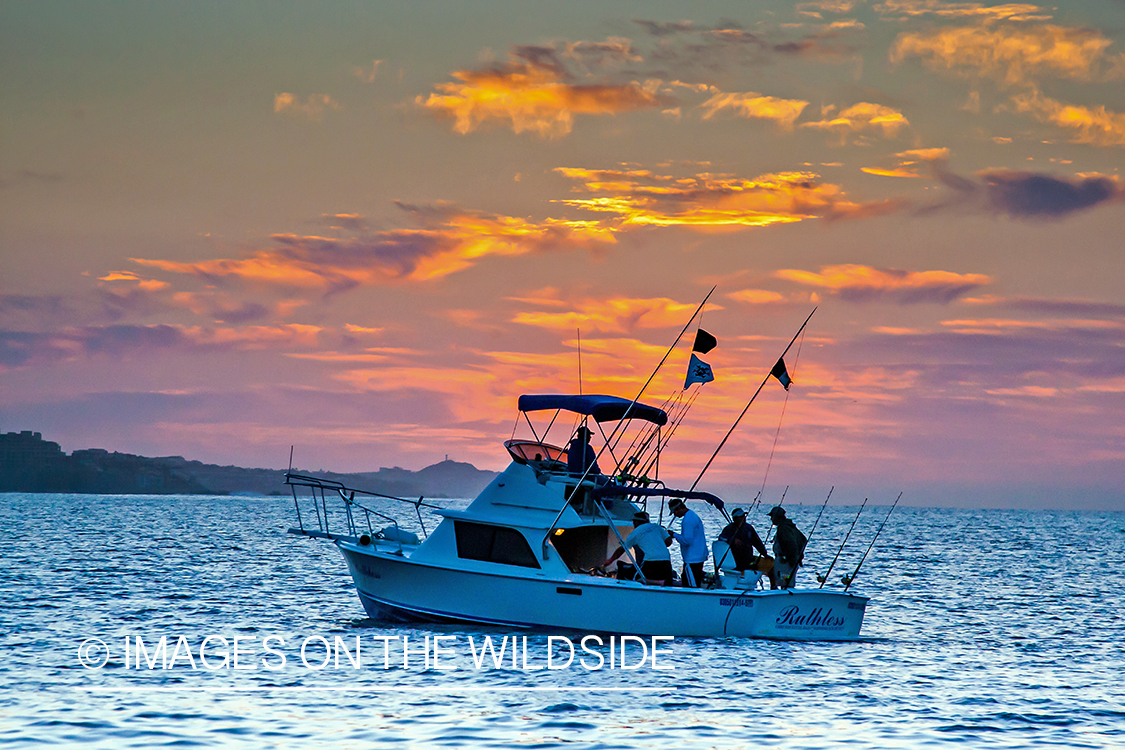 Fishermen on deep sea fishing boat with fishing rods.