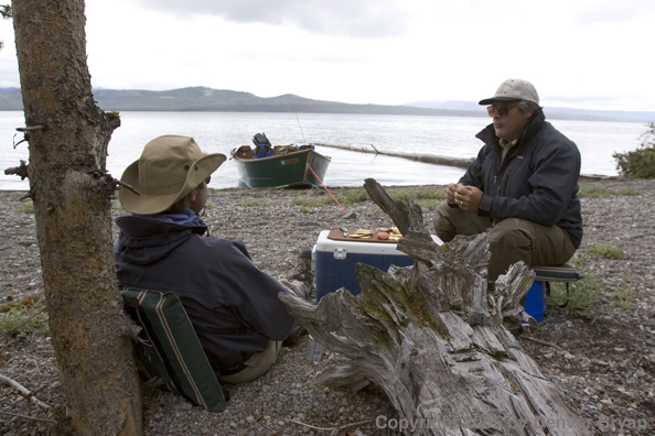 Flyfishermen eating lunch on shore of lake.