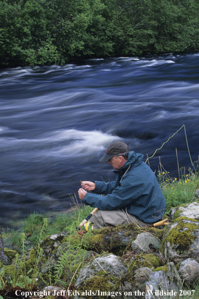 Flyfisherman ties fly on his double-handed rod