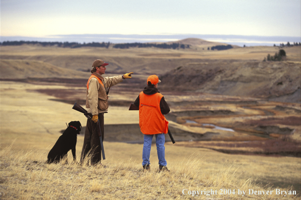 Father and son hunting with black Labrador Retriever.