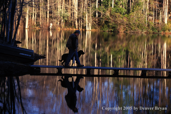 Black Labrador Retriever and trainer on dock