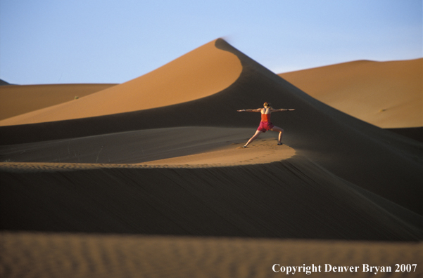 Woman stretching on sand dunes in Sossusvlei park, Namibia. Africa