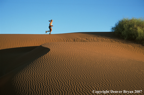 Woman running on sand dunes in Sossusvlei park, Namibia. Africa