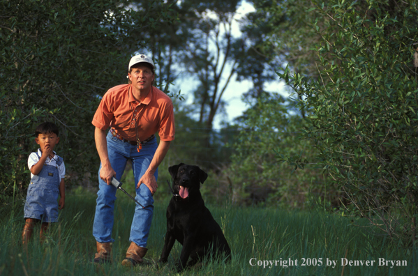 Trainer with black Labrador Retriever.