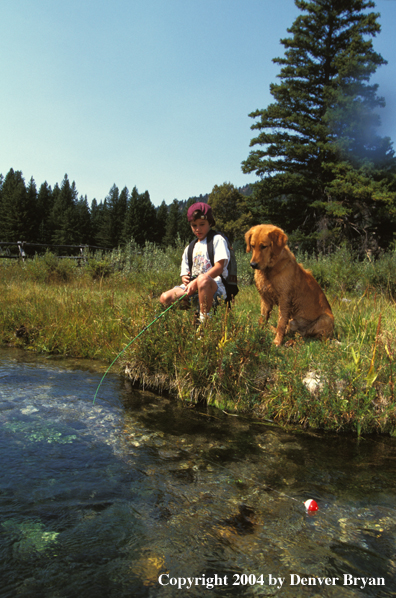 Boy spincast fishing with golden Retriever