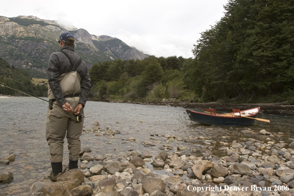 Flyfisherman checking out river.  Driftboat in background.