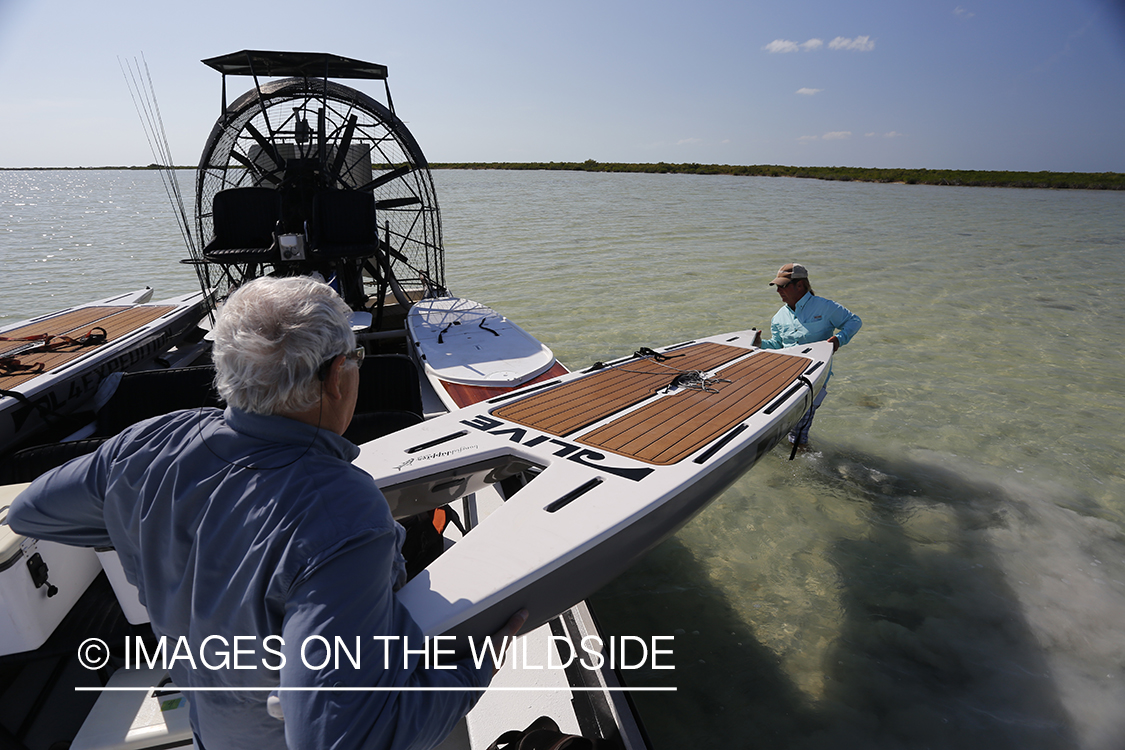 Flyfishermen unloading stand up paddle boards from airboat.