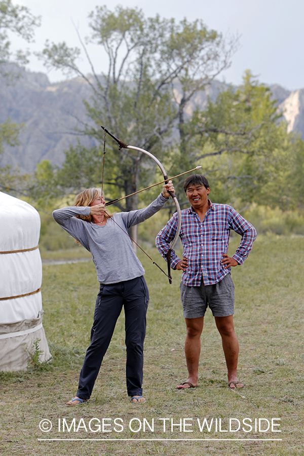 Mongolian man showing woman to shoot native bow.