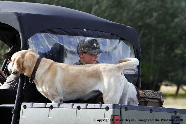 Young Hunter riding in back of ATV with dog