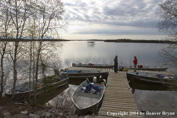 Fishermen on the dock with fishing boats tied up and float plane in the background.  Saskatchewan.