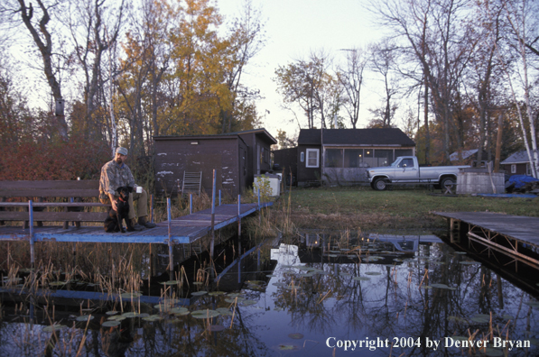 Waterfowl hunter with Lab on dock. 