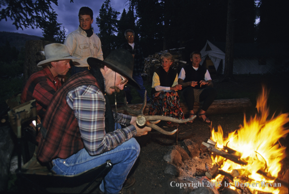 Cowboys and campers sitting around campfire.