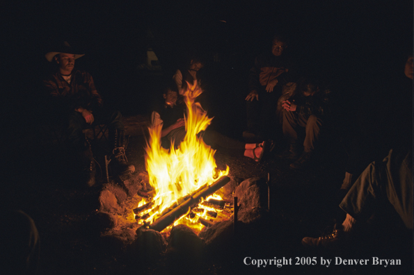 Cowboys and campers sitting around campfire.