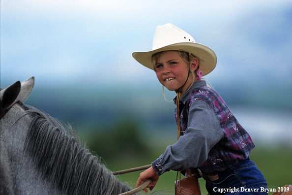 Young cowgirl on horse at rodeo