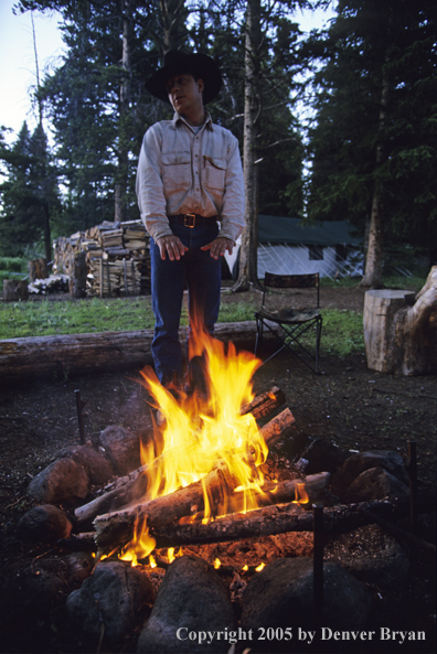 Cowboy standing by campfire.