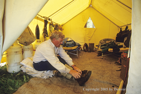 Flyfisherman gearing up in tent.