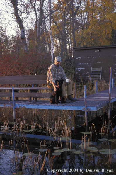 Waterfowl hunter with Lab on dock.