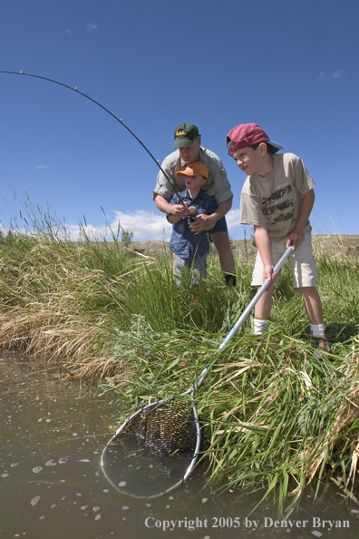 Father and sons fighting/landing trout.