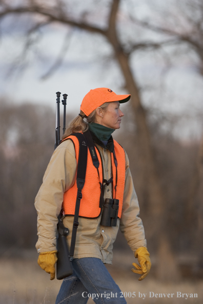 Woman big game hunter walking in field.