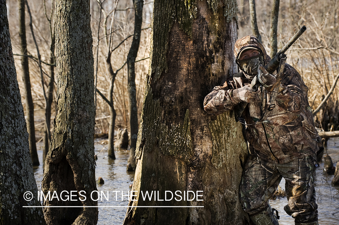 Waterfowl hunter camouflaged in wetlands.