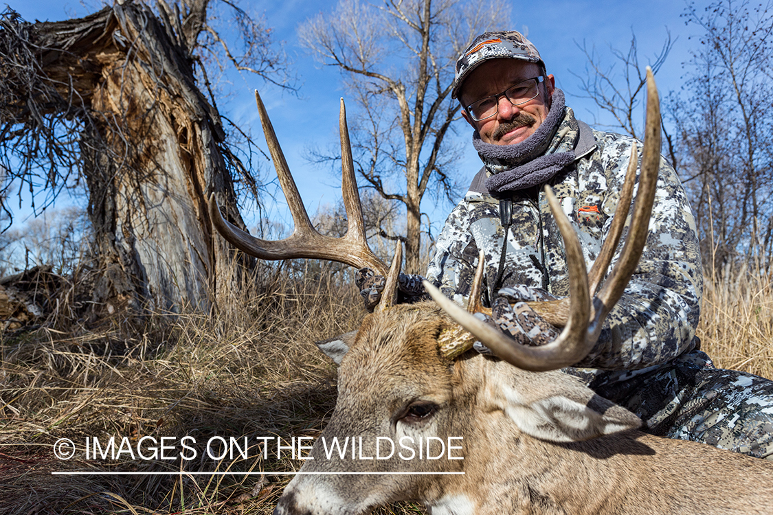 Bow hunter with downed white-tailed deer.