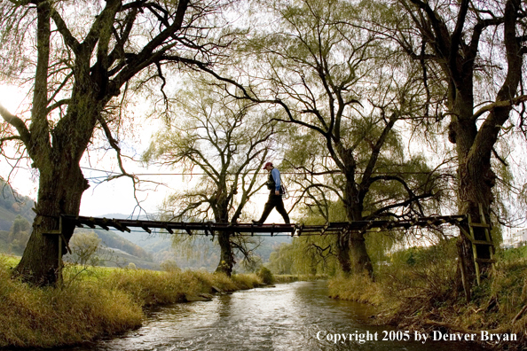 Flyfisherman crossing foot bridge on Pennsylvania spring creek.