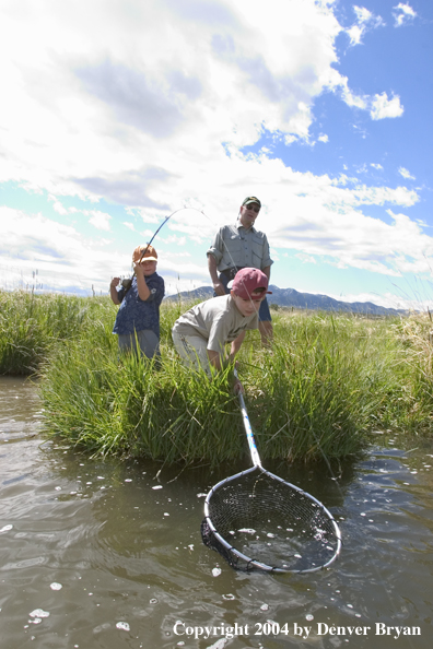 Father and sons fighting/landing trout.