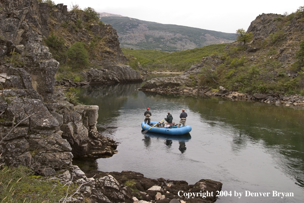 Flyfishermen floating river in raft.