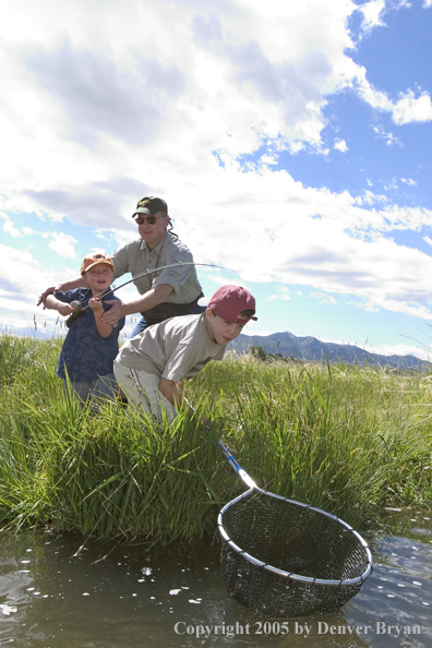 Father and sons fighting/landing trout.