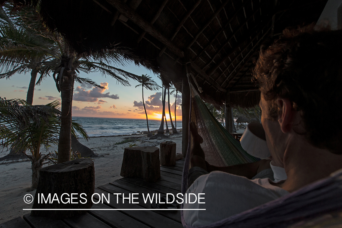 Flyfisherman relaxing in hammock at sunset.