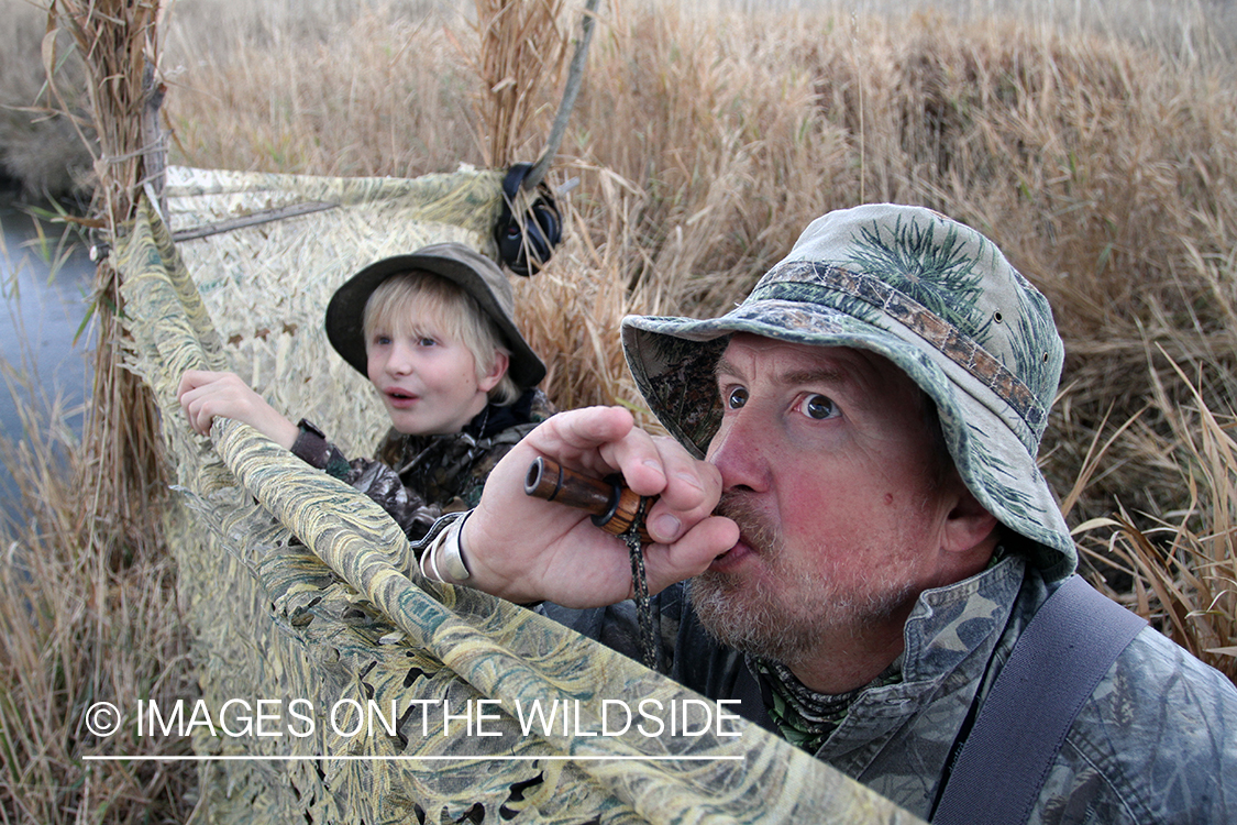 Father and son waterfowl hunters calling waterfowl. 