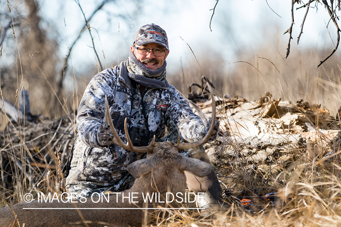 Bow hunter with downed white-tailed deer.