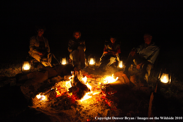 Family sitting by campfire on african safari