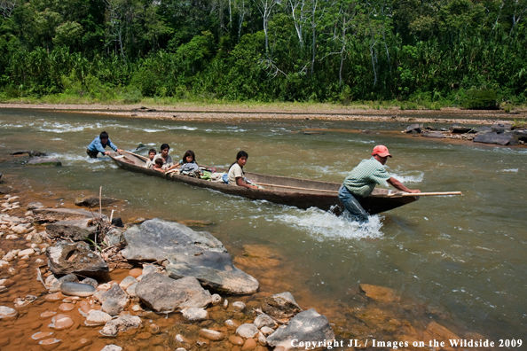 Local Bolivia natives pushing canoe upstream