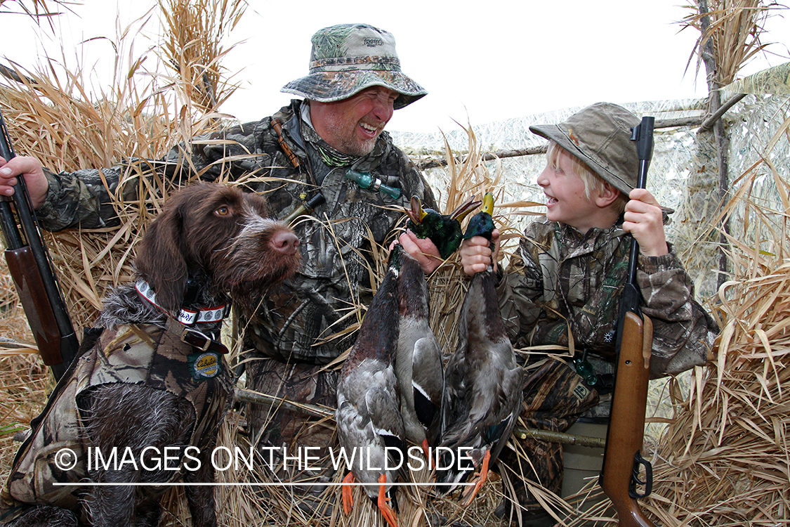 Father and son waterfowl hunters with bagged waterfowl.