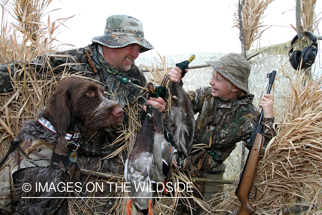 Father and son waterfowl hunters with bagged waterfowl.