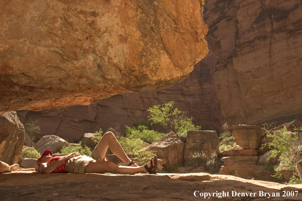 Hiker resting in shade along the Colorado River.  Grand Canyon.