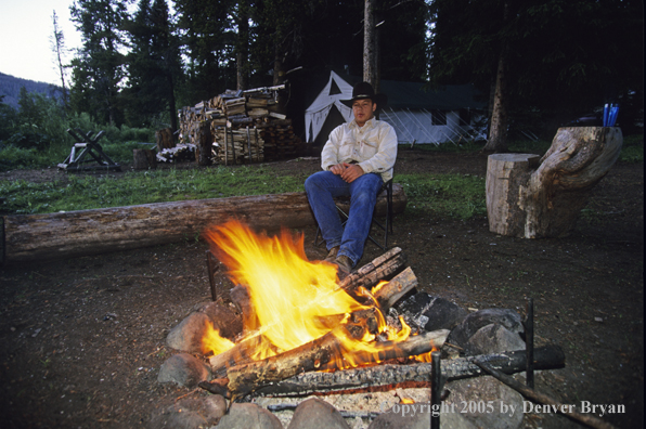 Cowboy sitting by campfire.