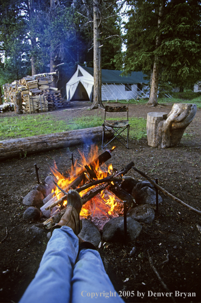 Cowboy reposing by campfire.