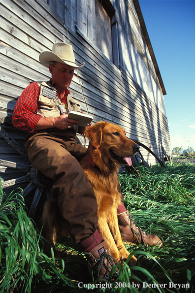 Flyfisherman choosing fly with Golden retriver.