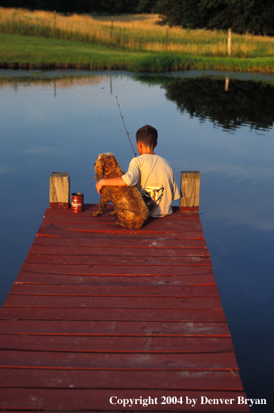 Boy spincast fishing with dog.