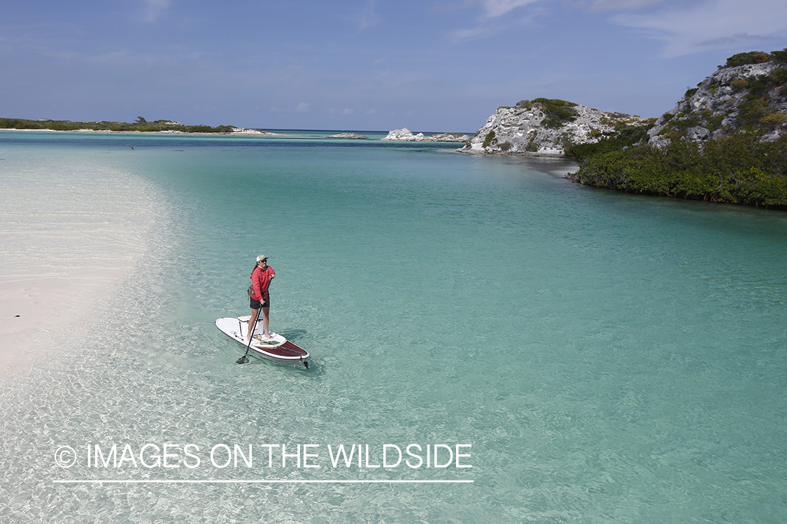 Saltwater flyfishing woman with stand up paddle board fishing flats.