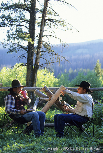 Cowboys eating and talking at edge of camp.