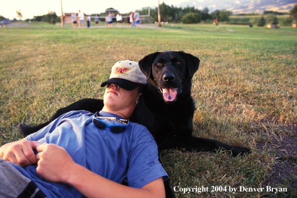 Owner using Black Labrador Retriever as pillow