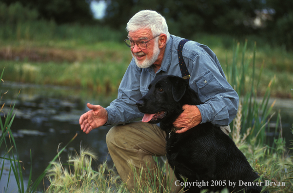 Trainer with black Labrador Retriever.